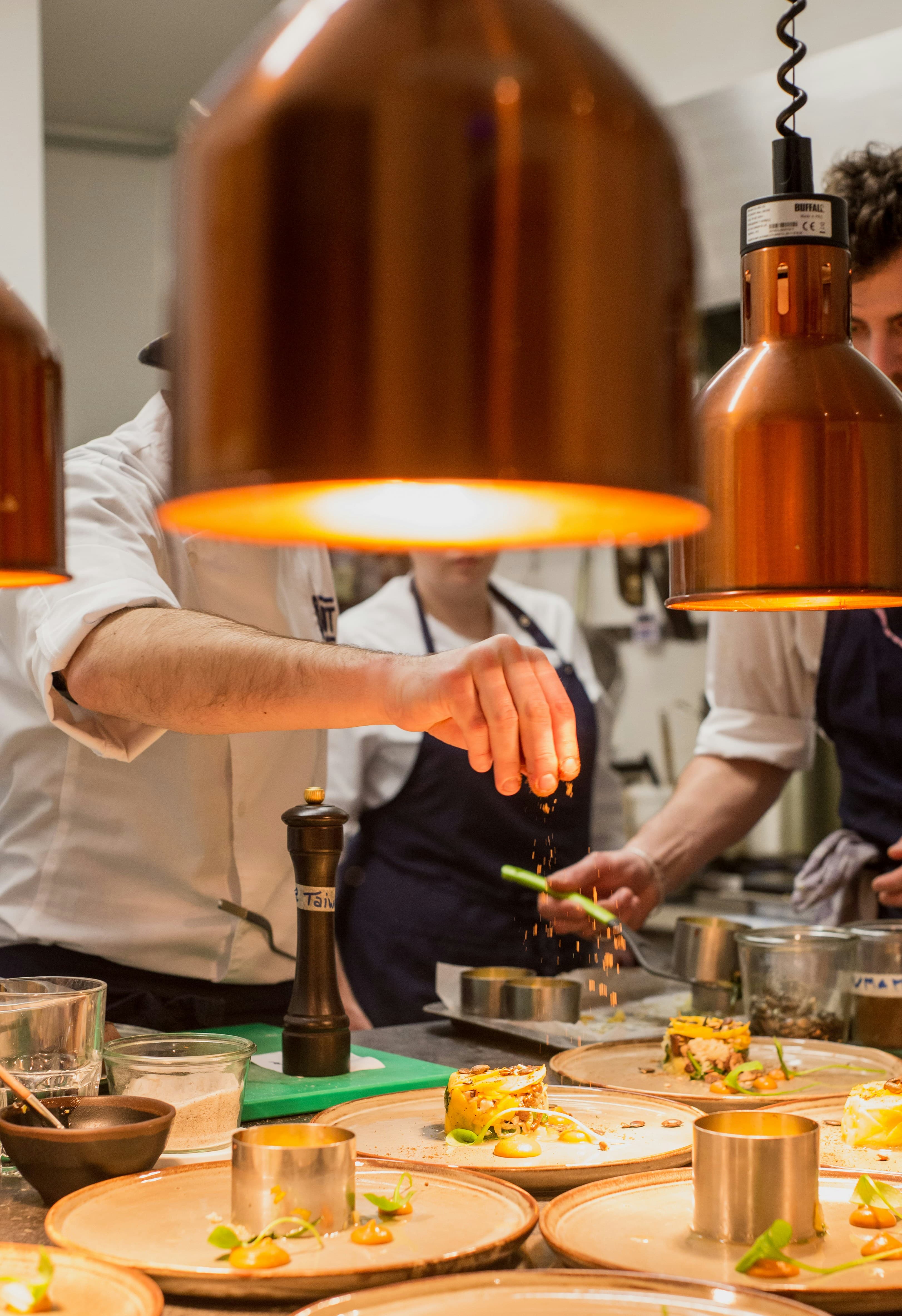A chef plating food in a warmly lit restaurant kitchen
