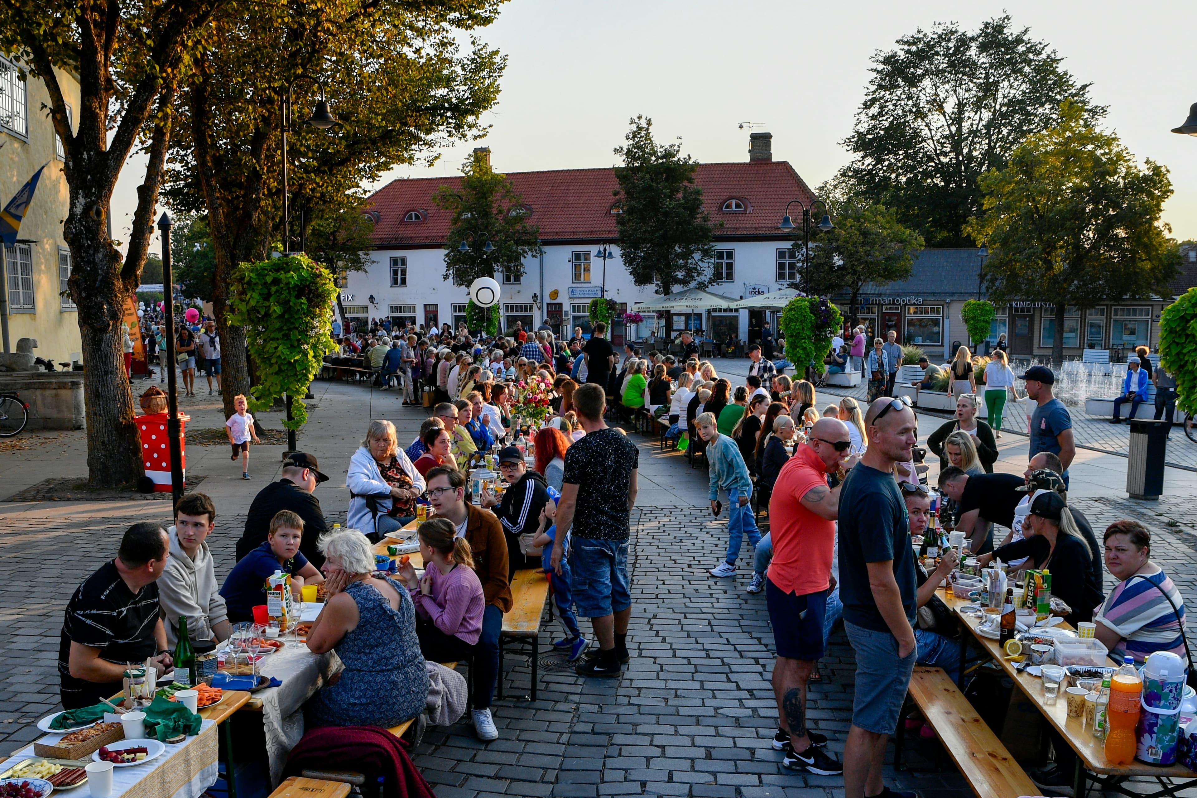 Neighbours sharing a meal at long tables outdoors at dusk